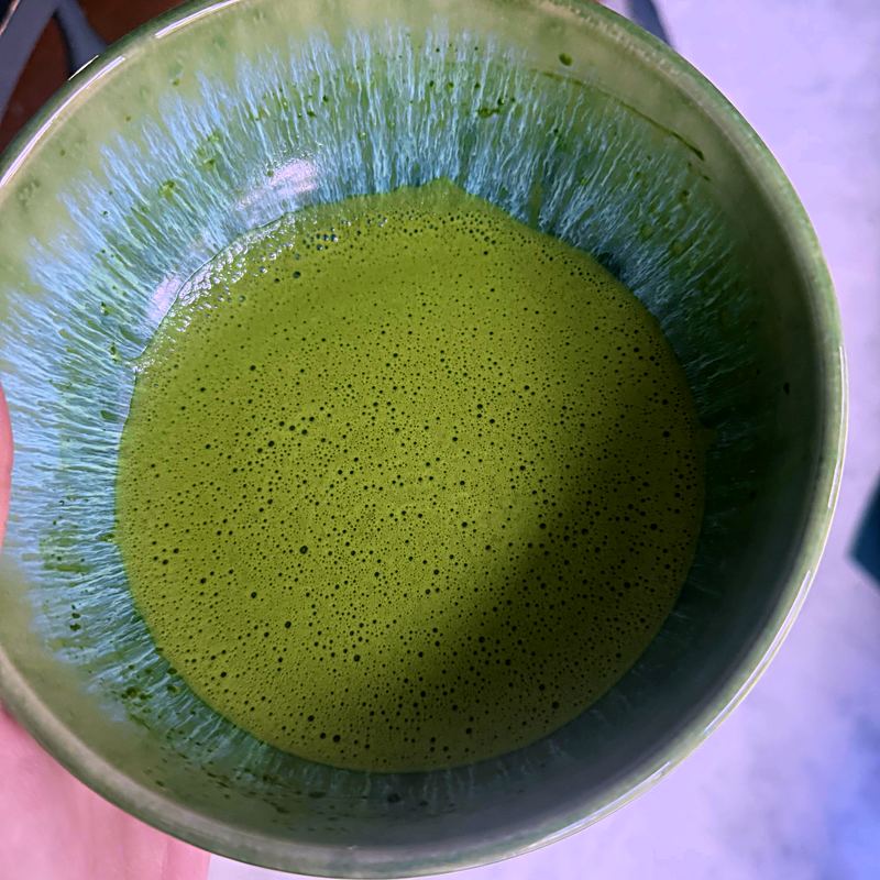 Customer photo: Vibrant green whisked matcha in ceramic bowl