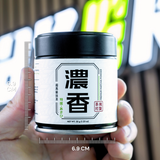 Jar of matcha powder held by a hand with measurement scale