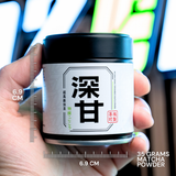 Hand holding a container of matcha powder with measurements and text on the label.