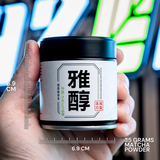 Hand holding a container of matcha powder with measurement details against a neon sign background
