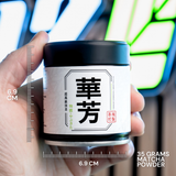 Hand holding a container of matcha powder with measurement details