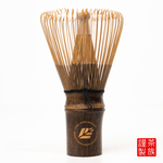 Traditional Japanese tea whisk with wooden handle on a white background